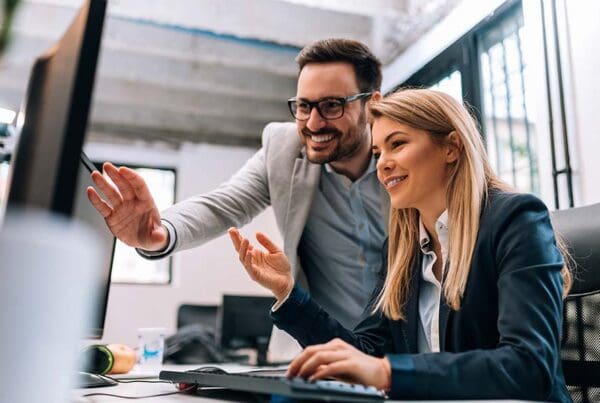 Employee Benefits for Small Businesses - Portrait of a Cheerful Business Man and Woman Looking at a Computer Together in the Office