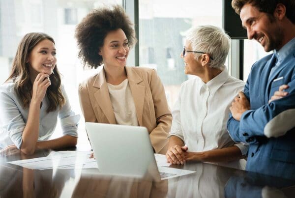 Key Person Life Insurance - Colleagues Laughing and Working Together in the Conference Room of a Modern Office with Lots of Light and Large Pane Glass Windows in the City