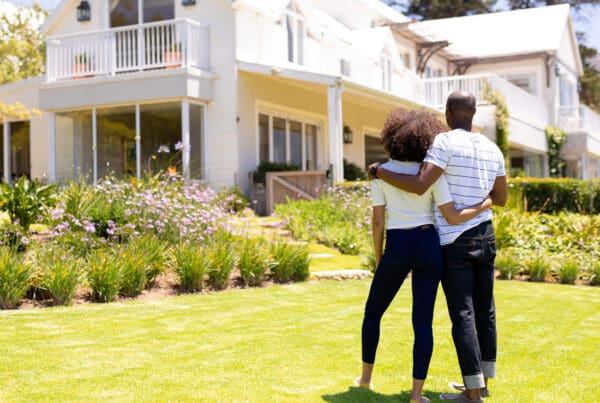 Personal Insurance - Young Couple Looking at a Big House While Standing on Their Lawn